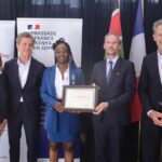 Krysteen Savane receives the Chevalier insignia from French Ambassador Arnaud Suquet in Kibera