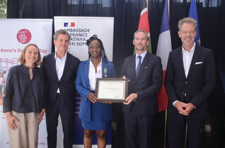 Krysteen Savane receives the Chevalier insignia from French Ambassador Arnaud Suquet in Kibera